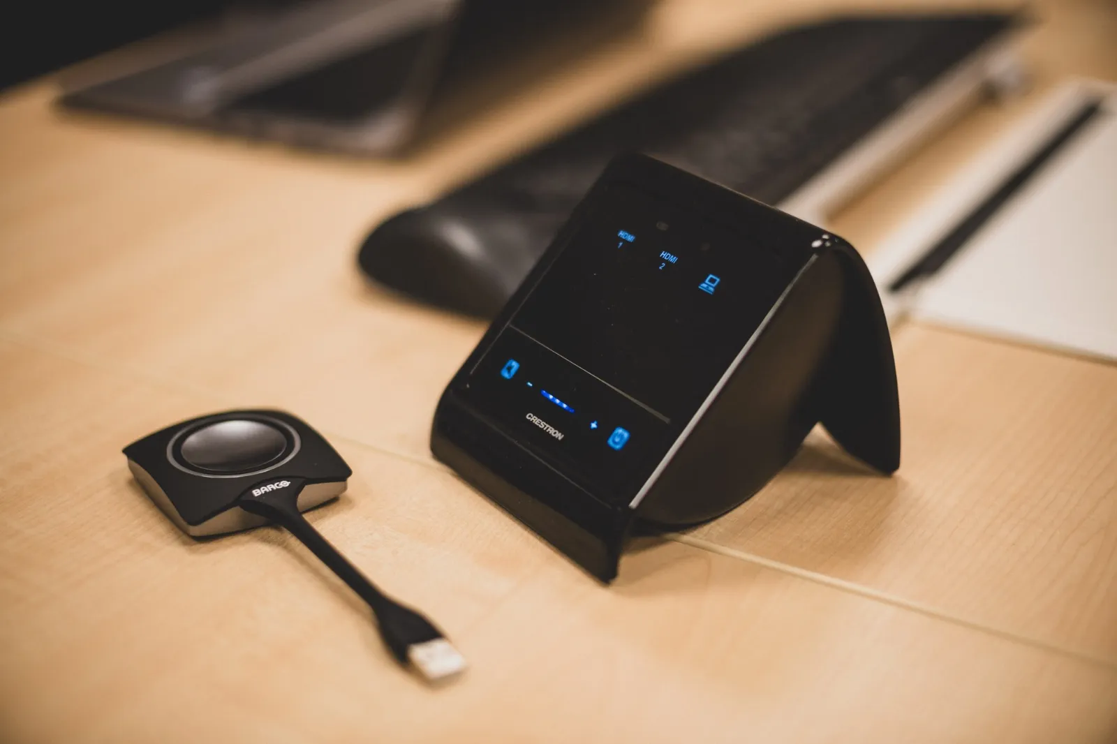Crestron pekpanel och Barco ClickShare-dongle på konferensbordet.