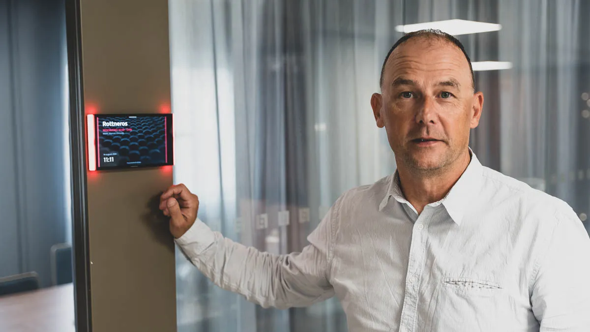 Marcus Ohlsson, IT-gruppchef på Länsförsäkringar Värmland, vid en digital bokningsdisplay utanför ett mötesrum.